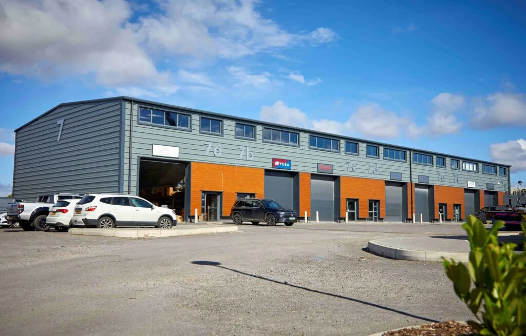 Unit 7 Capital Park Beverley: A light industrial style trade unit, faced in grey steel and brown wood. Carpark to foerground, with several parked cars shown