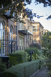 Partial side view of a row of office buildings (2 storey, brick-built) The closest building shows a black metal balcony railing