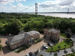 View from height of 2 office buildings, trees, the River Humber, and the Humber Bridge in the background