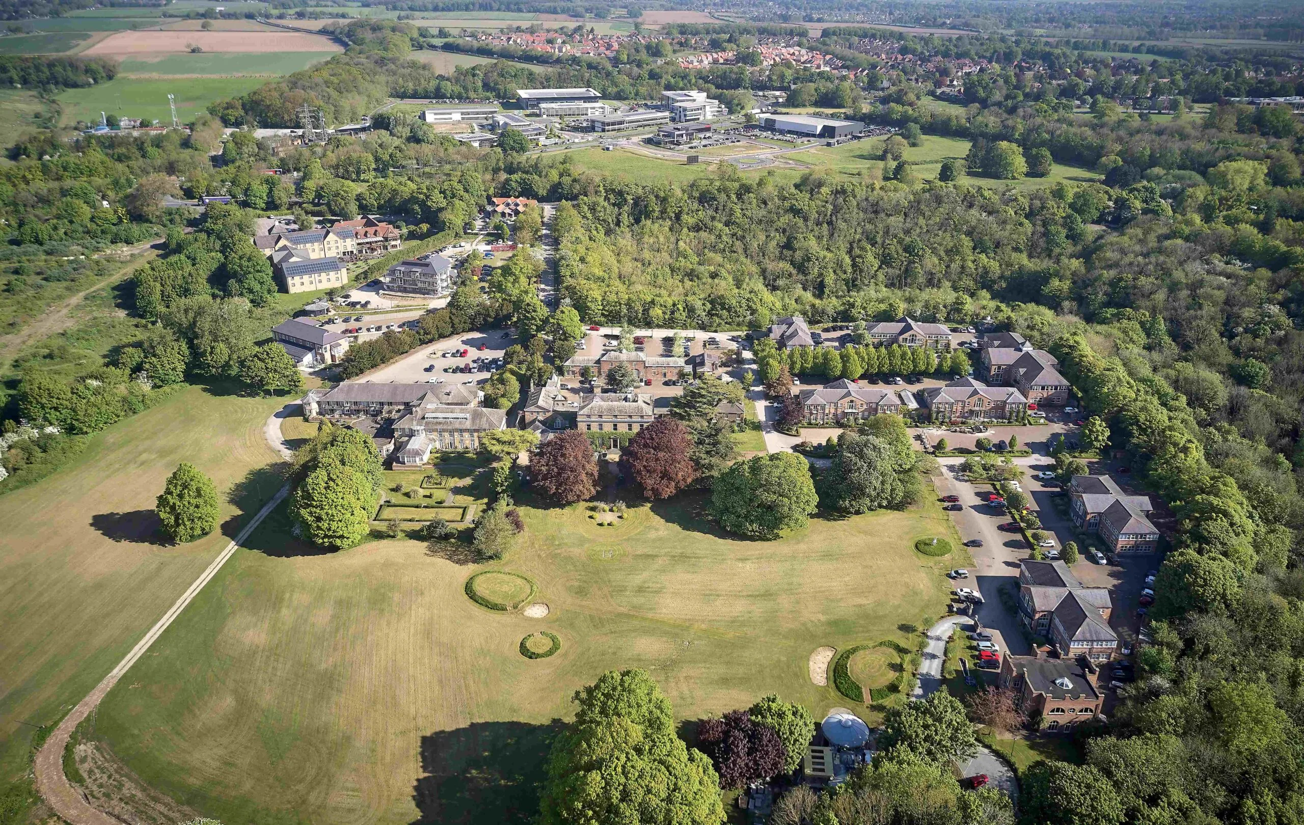 High-angle aerial shot of the Hesslewood Office Park showing a cluster of buildings surrounded by vast green parkland and trees