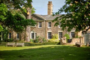 View across grassland of a 2 story brick built building,