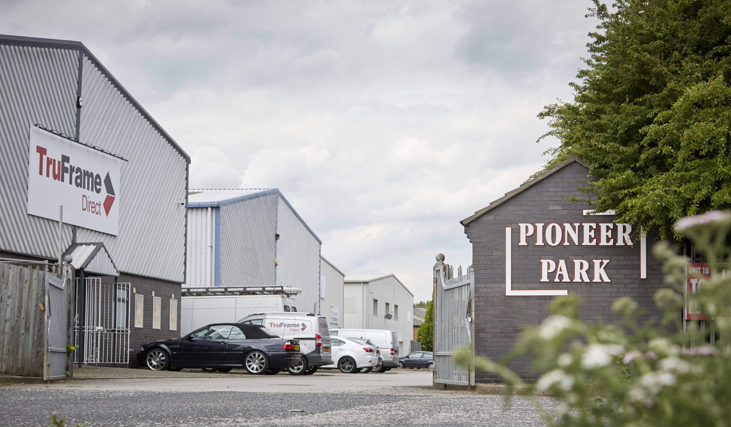 View of several light industrial units, in a row. Signage for TruFrame Direct and Pioneer Park visible on 2 units. 