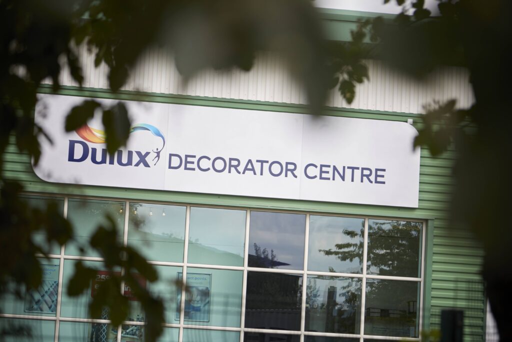 Partial view of a green steel clad light industrial unit. Signage for Dulux on the building.