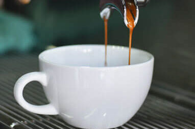 Close up image of coffee machine dispensing coffee into a white cup