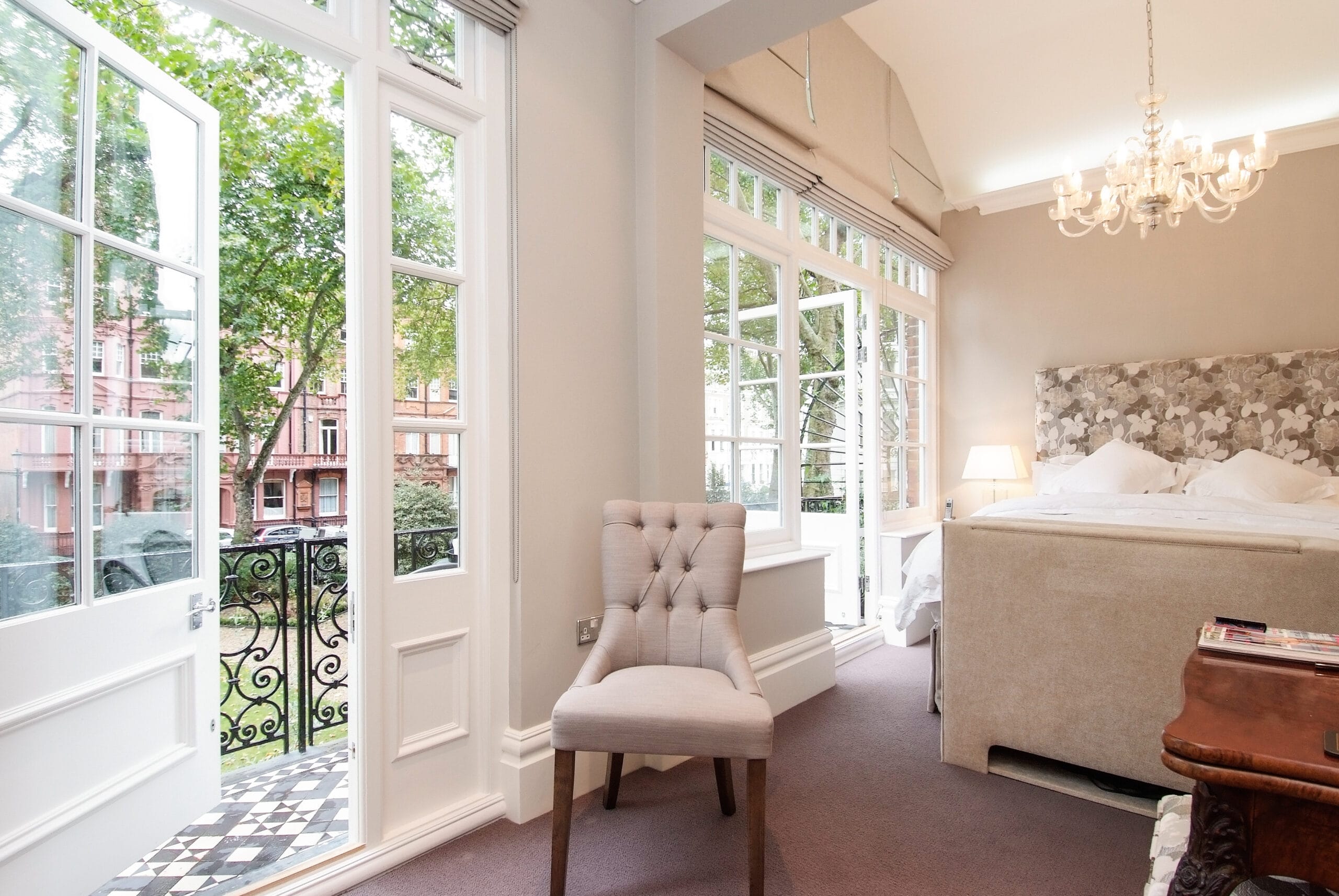 Double bedroom decorated in whites and neutral colours. French doors leading to tiled balcony.