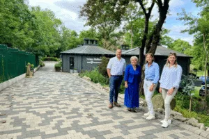 4 people stood on a stone pathway, including Anne Handley, Leader of East Riding Council, in front of some tree top styled offices, in woodland setting